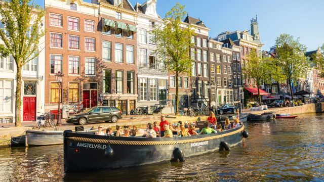 Un remorqueur Mokumboot avec skipper navigue sur l&rsquo;Amstel, pr&egrave;s de l&rsquo;embl&eacute;matique Magere Brug &agrave; Amsterdam.